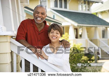 Stock Photograph - African American middle aged couple standing together on stairs outside home.. Fotosearch