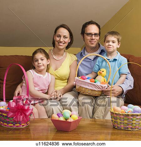 Stock Photograph - Caucasian family on couch holding Easter basket and looking at viewer.. Fotosearch
