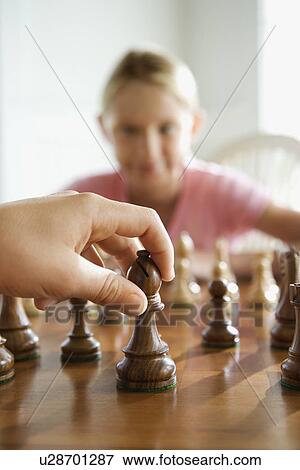 Caucasian hand moving chess piece with pre-teen girl watching in background. View Large Photo Image Stock Photo - Caucasian hand moving chess piece with pre-teen girl watching in background.. Fotosearch