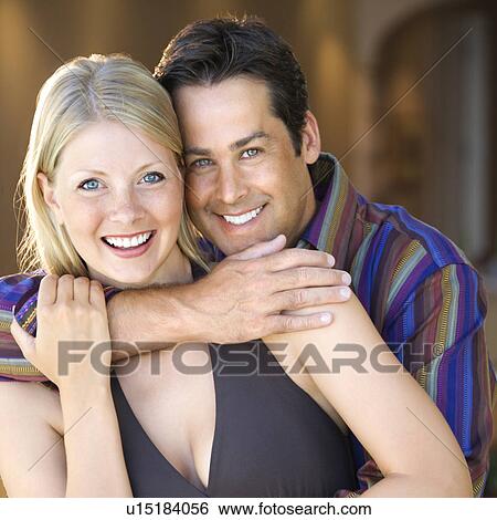 Caucasian mid adult couple embracing and smiling at viewer. View Large Photo Image Stock Photograph - Caucasian mid adult couple embracing and smiling at viewer.. Fotosearch