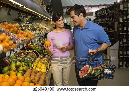 Stock Image - Caucasian mid-adult couple grocery shopping for fruit.. Fotosearch