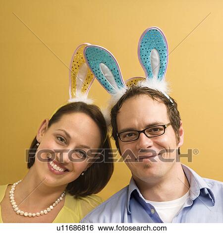 Stock Photograph - Caucasian mid adult couple wearing rabbit ears and looking at viewer.. Fotosearch