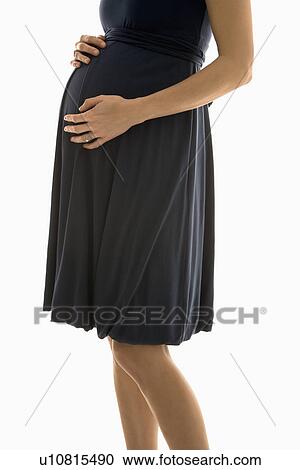 Stock Image - Caucasion mid-adult pregnant woman with hands on belly.. Fotosearch