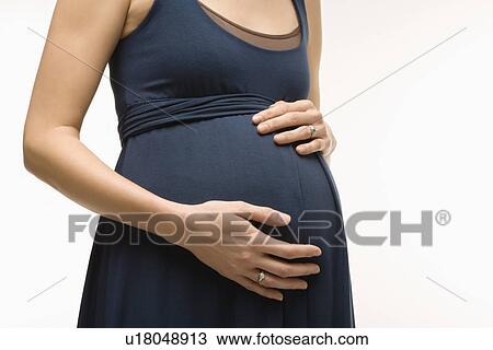 Stock Image - Caucasion mid-adult pregnant woman with hands on belly.. Fotosearch