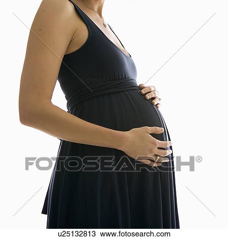 Stock Image - Caucasion mid-adult pregnant woman with hands on belly.. Fotosearch