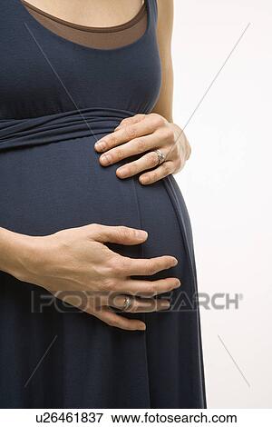 Stock Photo - Caucasion mid-adult pregnant woman with hands on belly.. Fotosearch