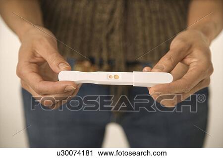 Stock Image - Close up of Asian woman holding pregnancy test.. Fotosearch