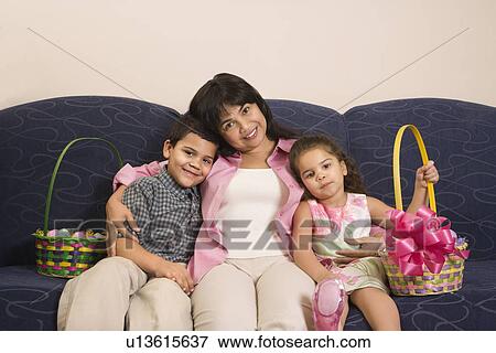 Stock Photo - Family sitting on couch with Easter baskets smiling and looking at viewer.. Fotosearch