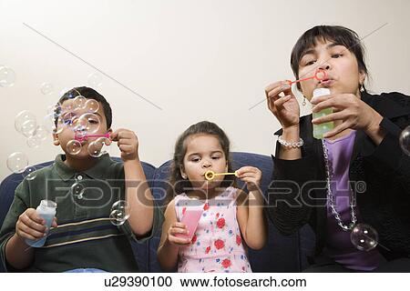 Family sitting together blowing soap bubbles. View Large Photo Image Stock Image - Family sitting together blowing soap bubbles.. Fotosearch
