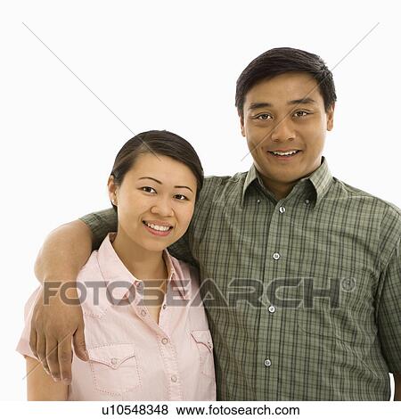 Stock Photo - Mid adult Asian couple with arms around eachother smiling.. Fotosearch