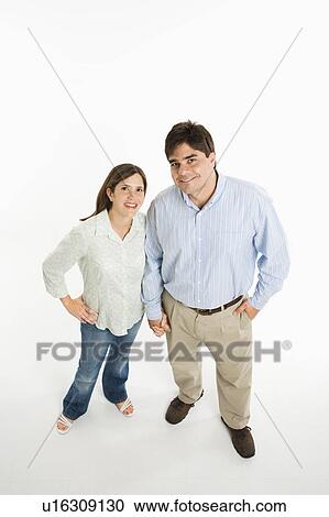 Stock Image - Overview of couple standing smiling against white background.. Fotosearch