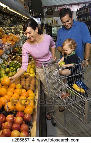 Picture - Parents grocery shopping for fruit with toddler. Fotosearch