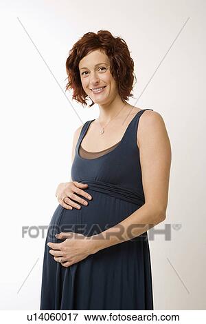 Stock Photo - Portrait of Caucasion mid-adult pregnant woman with hands on belly looking at viewer and smiling.. Fotosearch
