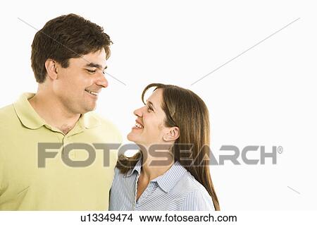 Picture - Portrait of smiling couple looking at eachother against white background.. Fotosearch