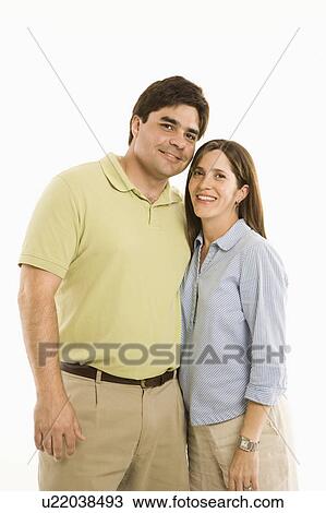 Stock Image - Portrait of smiling couple standing against white background.. Fotosearch