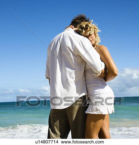 Picture - Attractive couple in embrace on Maui, Hawaii beach.. Fotosearch