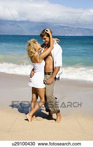 Stock Image - Attractive couple in sensual embrace on Maui, Hawaii beach. Fotosearch