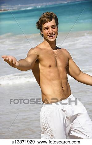 Stock Photo - Attractive man walking on Maui, Hawaii beach smiling and reaching out. Fotosearch