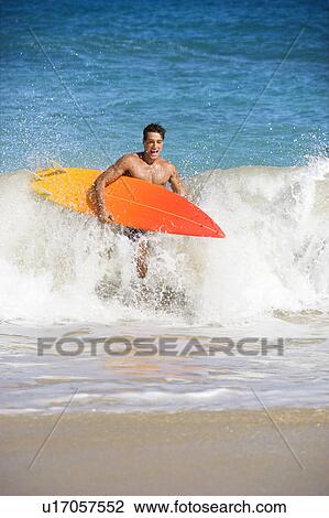 Attractive young man running out of water carrying surfboard in Maui, Hawaii. View Large Photo Image Stock Image - Attractive young man running out of water carrying surfboard in Maui, Hawaii.. Fotosearch