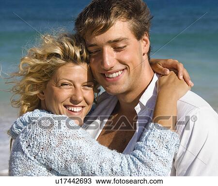 Stock Image - Couple embracing on beach. Fotosearch