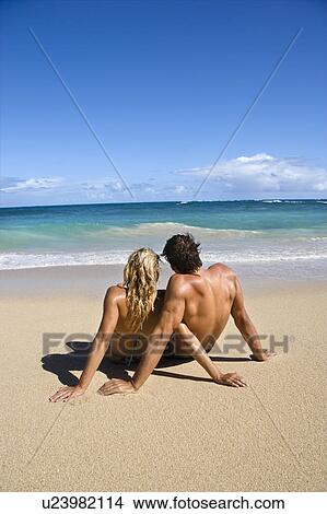Picture - Couple sitting close together on Maui, Hawaii beach looking out at ocean.. Fotosearch