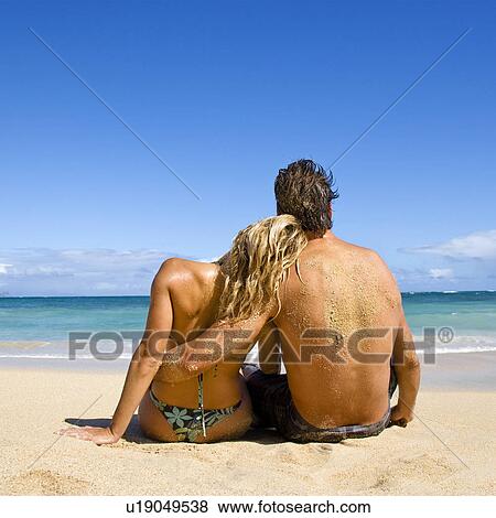 Stock Photo - Couple sitting on beach. Fotosearch