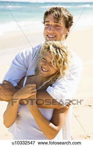 Stock Photo - Happy couple embracing on Maui, Hawaii beach.. Fotosearch