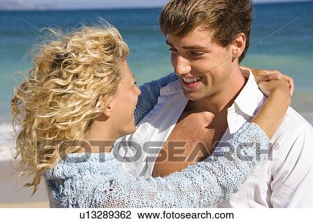 Stock Image - Happy smiling couple embracing on Maui, Hawaii beach. Fotosearch