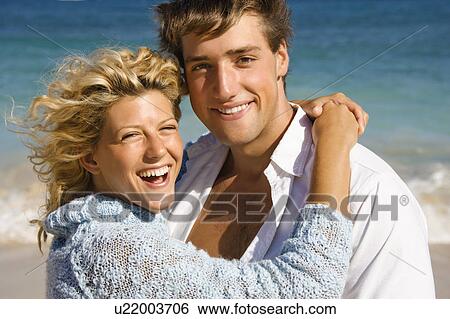 Stock Photograph - Happy smiling couple embracing on Maui, Hawaii beach.. Fotosearch