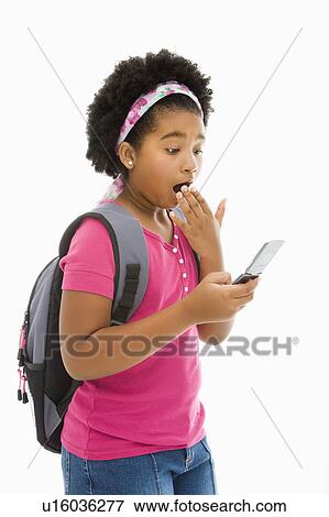Stock Photo - African American girl with backpack looking at cell phone with surprised expression.. Fotosearch