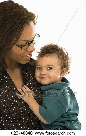 Stock Image - African American mid adult mom holding toddler son who is looking at viewer.. Fotosearch