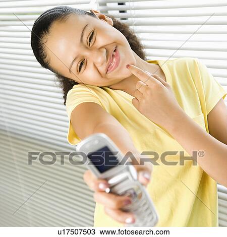 African American preteen girl holding cell phone out to viewer and smiling. View Large Photo Image Stock Image - African American preteen girl holding cell phone out to viewer and smiling.. Fotosearch