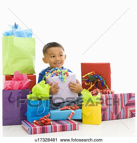 Stock Image - Asian boy sitting smiling with wrapped presents.. Fotosearch