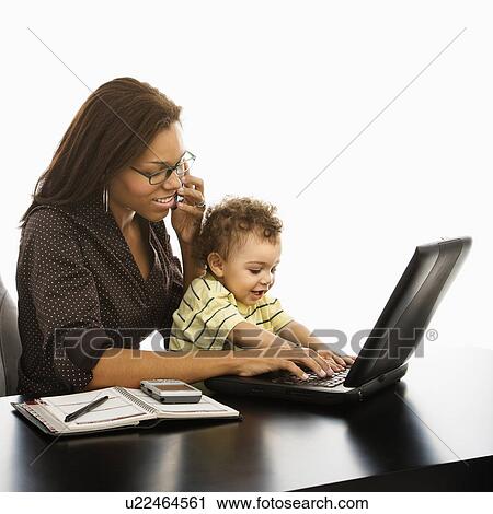 Businesswoman at work on laptop and cell phone with toddler son on lap View Large Photo Image Stock Image - Businesswoman at work on laptop and cell phone with toddler son on lap. Fotosearch