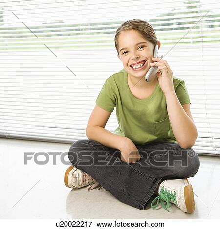 Caucasian preteen girl sitting on floor talking on cell phone and smiling at viewer. View Large Photo Image Stock Photo - Caucasian preteen girl sitting on floor talking on cell phone and smiling at viewer.. Fotosearch