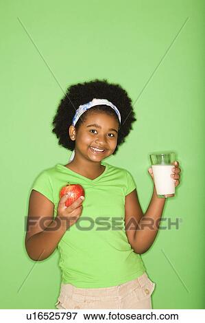 Girl holding glass of milk and apple View Large Photo Image Stock Photo - Girl holding glass of milk and apple. Fotosearch
