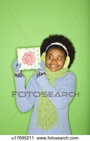 Stock Image - Girl in winter clothing holding wrapped package. Fotosearch