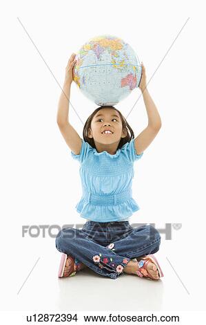 Picture - Girl sitting on floor holding Earth globe over her head. Fotosearch
