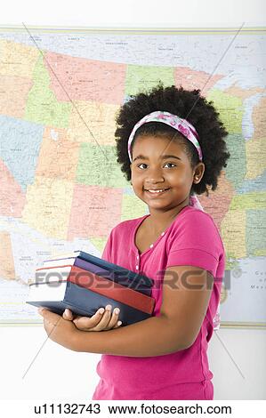 Girl standing in front of map holding stack of books View Large Photo Image Stock Image - Girl standing in front of map holding stack of books. Fotosearch