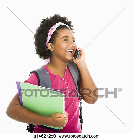 Stock Image - Girl with books and wearing backpack talking on cell phone. Fotosearch