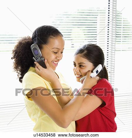 Girls holding cell phones up to each others ears View Large Photo Image Stock Photo - Girls holding cell phones up to each others ears. Fotosearch