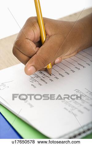 Hand of African American girl at school desk writing in notebook with pencil. View Large Photo Image Stock Photo - Hand of African American girl at school desk writing in notebook with pencil.. Fotosearch