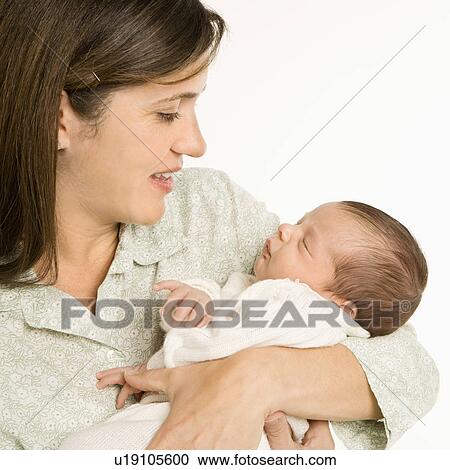 Stock Image - Mother holding baby smiling against white background.. Fotosearch
