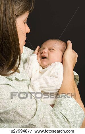 Mother smiling holding baby against black background. View Large Photo Image Stock Photo - Mother smiling holding baby against black background.. Fotosearch