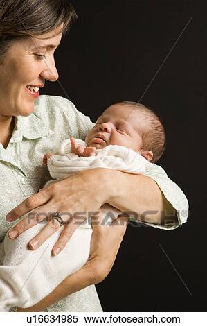 Mother smiling holding baby against View Large Photo Image Stock Photography - Mother smiling holding baby against . Fotosearch