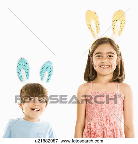 Stock Photo - Portrait of boy and girl wearing rabbit ears smiling.. Fotosearch