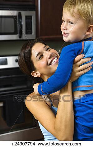 Woman in kitchen lifting son View Large Photo Image Picture - Woman in kitchen lifting son. Fotosearch
