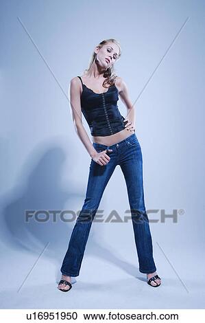 Stock Image - Blue toned full length studio portrait of pretty blonde Caucasian young woman.. Fotosearch