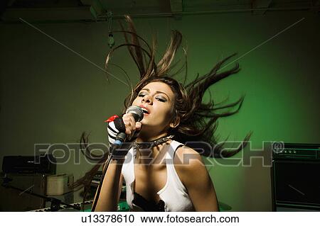 Caucasian female swinging head and hear while singing into microphone. View Large Photo Image Stock Image - Caucasian female swinging head and hear while singing into microphone.. Fotosearch