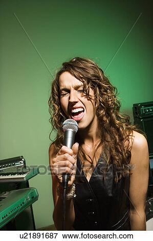 Female singing into microphone View Large Photo Image Stock Photo - Female singing into microphone. Fotosearch
